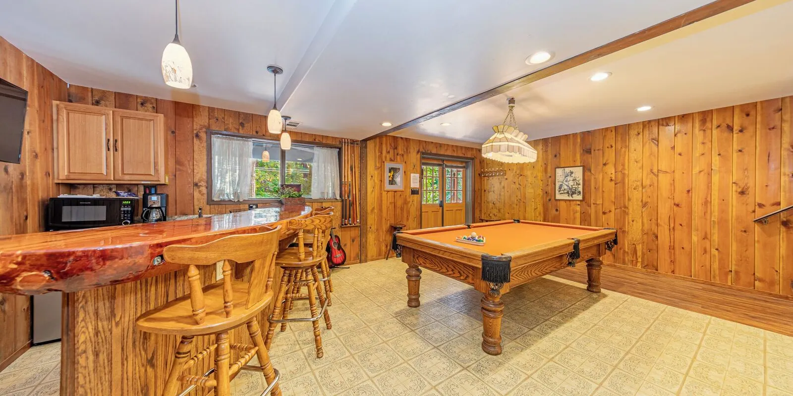 The game room: a pool table, a burl wood bar, a piano and a dart wall