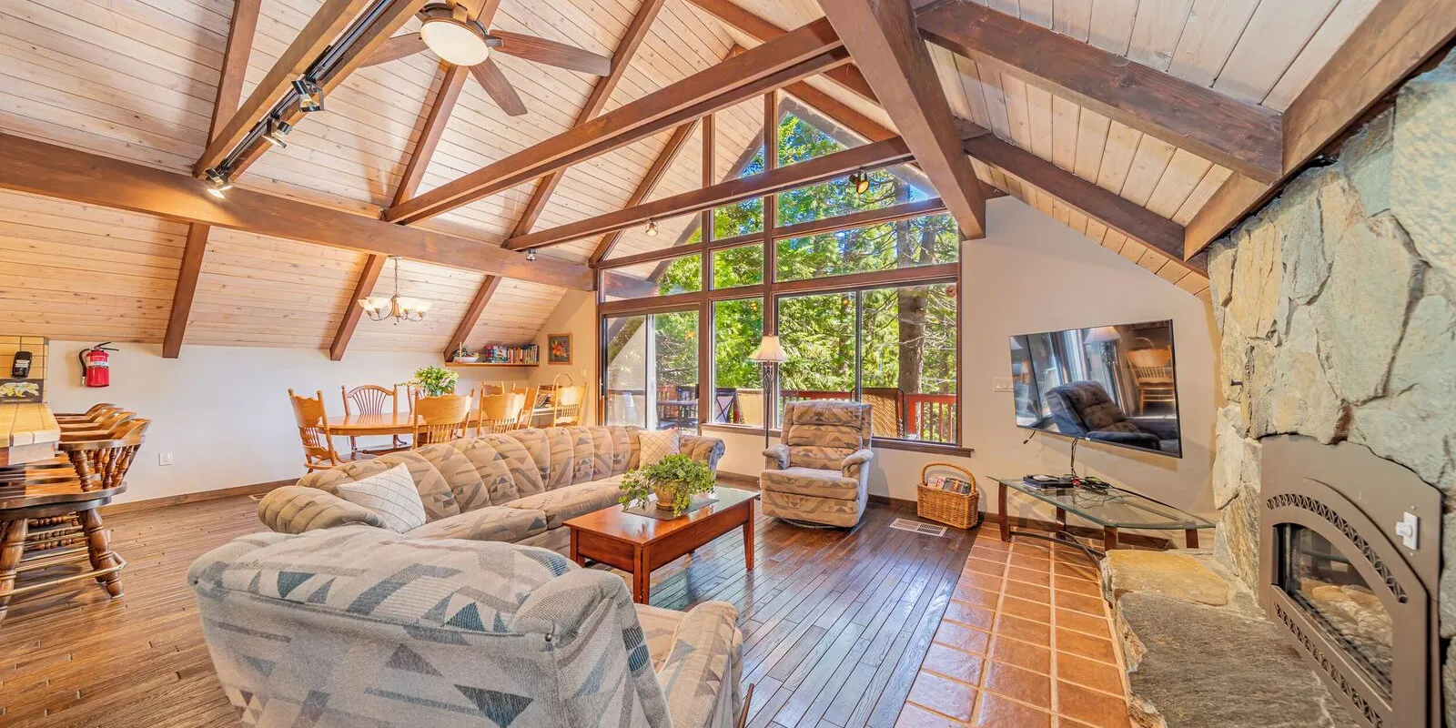 The living room: a gas fireplace set in stone, under the A-frame's beams and windows